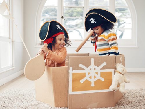 Playing, box ship and pirate kids role play, fantasy imagine or pretend as yacht captain in cardboa.